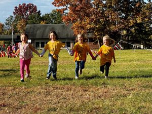 FOUR YOUNG STUDENTS HOLDING HANDS RUNNING 