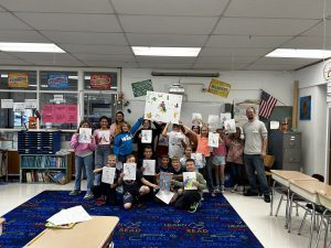 students gathered together holding up the pictures they colored