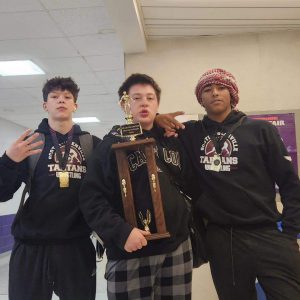 Three wrestlers standing together with their trophy