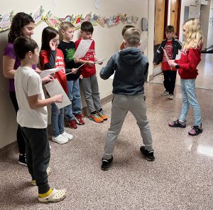 students standing in the hallway holding papers