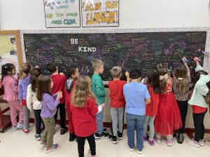 kids gathered around chalkboard filled with messages in colored chalk