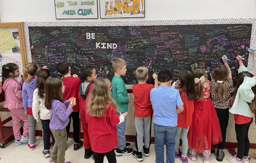 kids gathered around chalkboard filled with messages in colored chalk