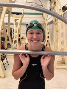 swimmer wearing suit and cap with goggles on top