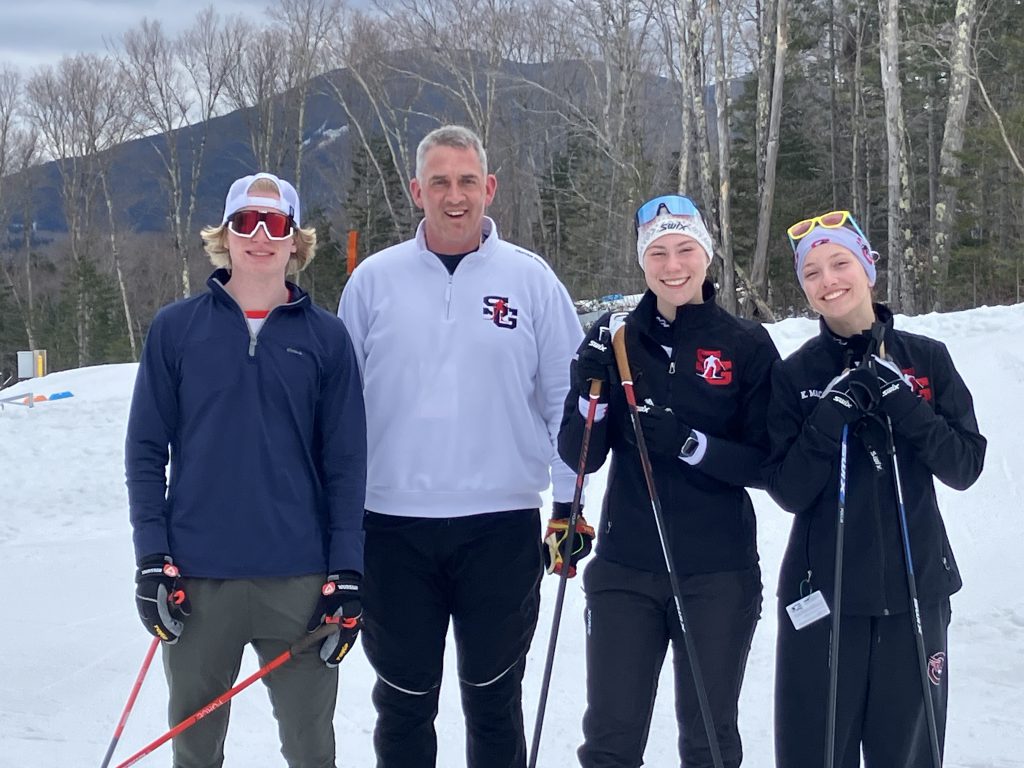 Ski Coach with three high school skiers in snowy background