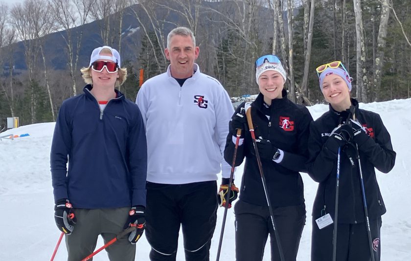 Ski Coach with three high school skiers in snowy background