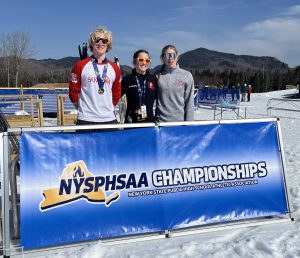 three students standing behind a NYSPHSAA banner