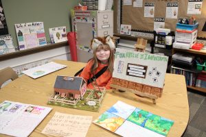 student sitting with project about foxes wearing fox ears