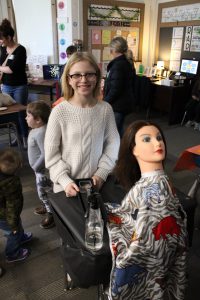 student smiling with her invention which includes a mannequin
