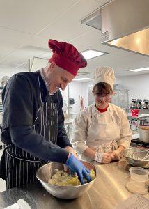 making pasta from dough in a silver bowl in a school kitchen setting