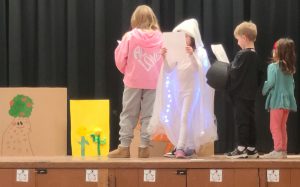 students reading papers on stage in costumes
