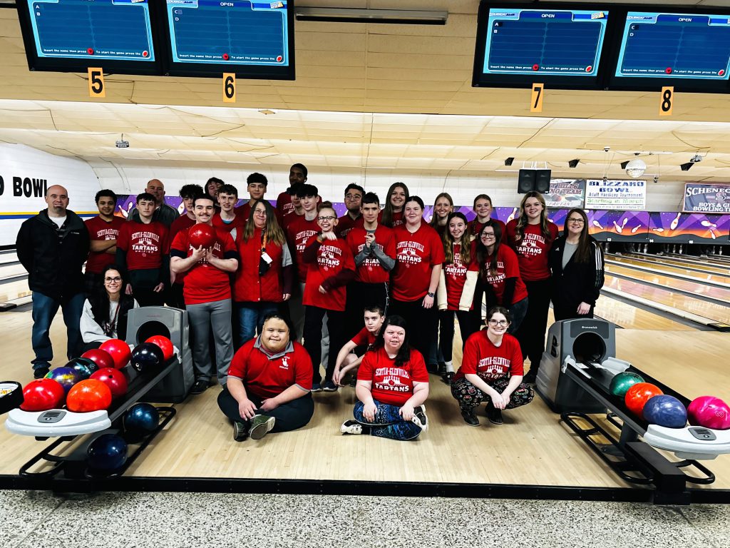 bowling team sitting and standing together on the lanes