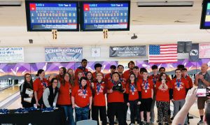 bowling team in red shirts, wearing medals with a look of excitement 