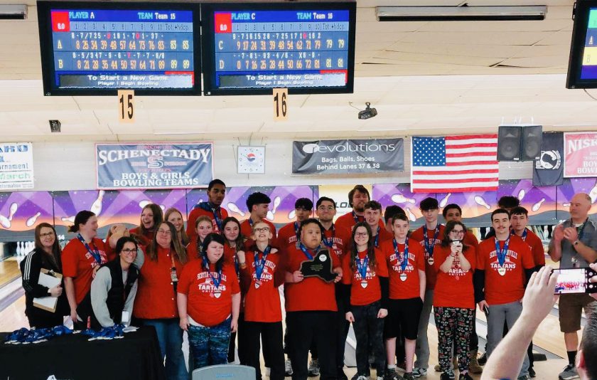 bowling team in red shirts, wearing medals with a look of excitement