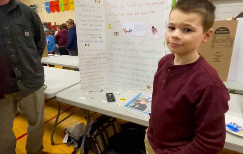 student in front of project at science fair