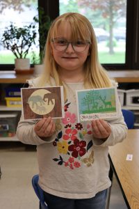 student holding up two cards she made