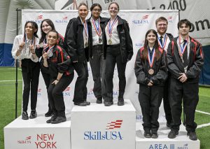 students standing on podium wearing medals and black SkillsUSA jackets